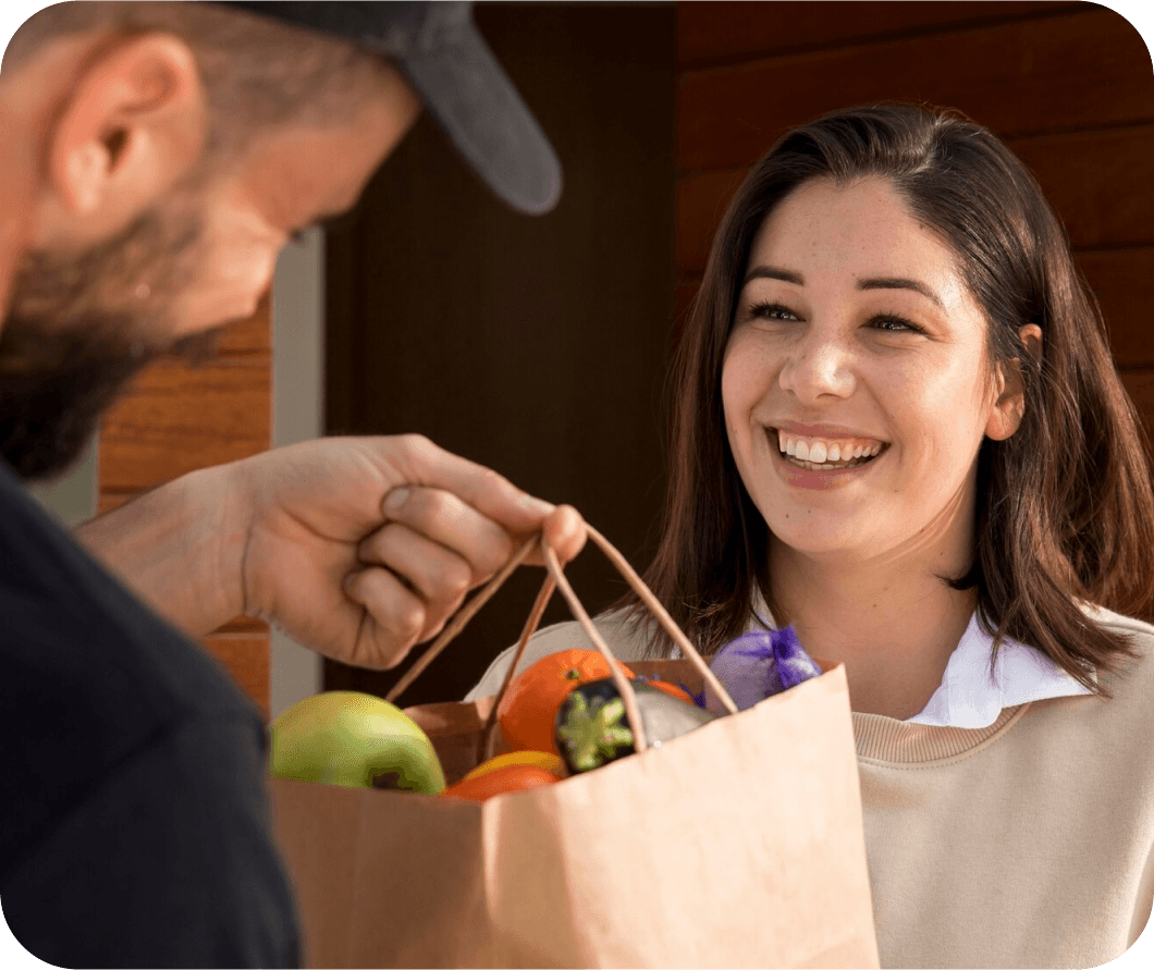 Un livreur Smood remettant les courses commandées à une cliente  devant sa porte.
