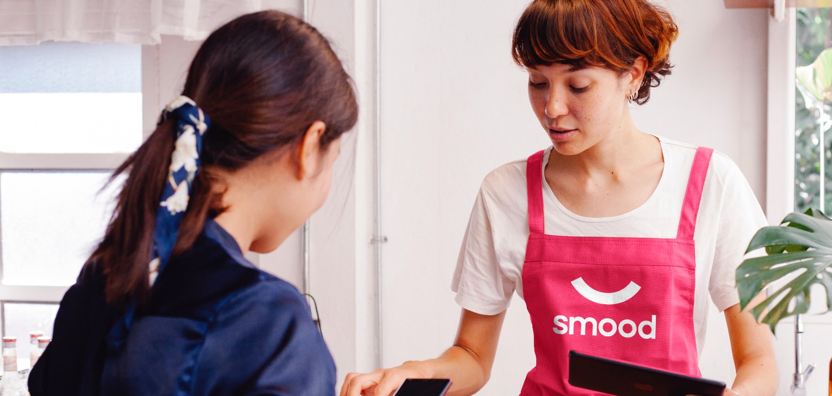Una cliente che parla con un partner Smood per ritirare il suo ordine effettuato su una piattaforma Smood.